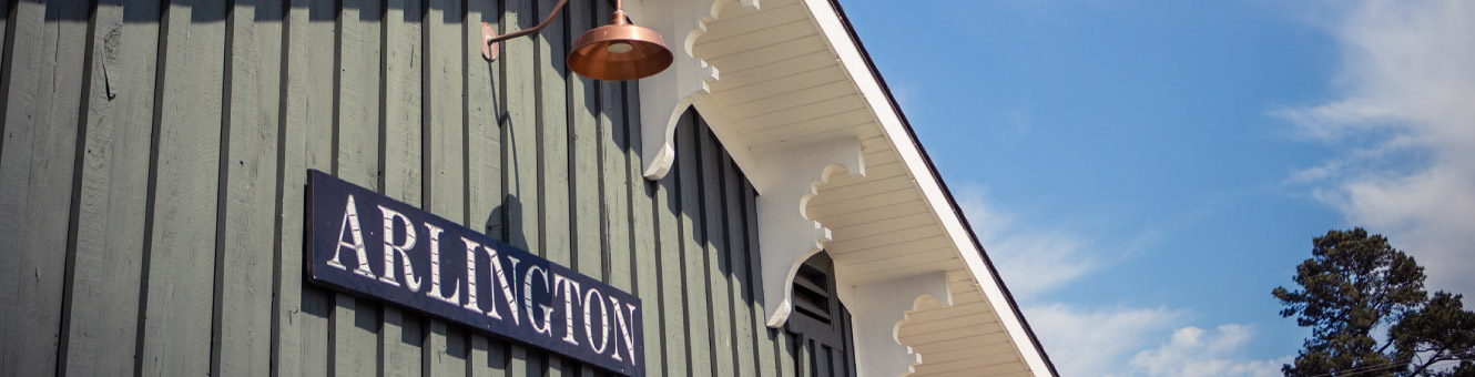 Close up of a blue sign on top of a wooden building that reads, "ARLINGTON"